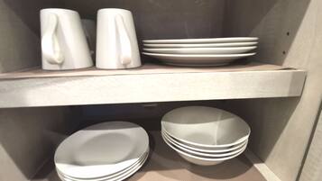 A shelf with white mugs and plates.