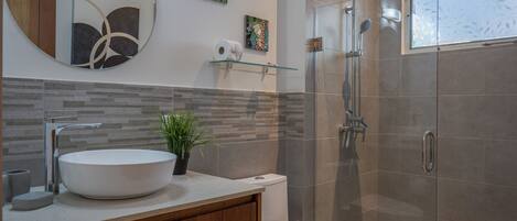 A modern bathroom with a large sink, toilet, and shower.