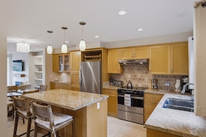 A modern kitchen with granite countertops, stainless steel appliances, and wooden cabinetry.