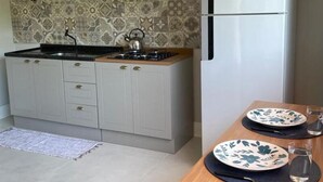 A compact kitchen with a microwave, stove, and refrigerator. - Studio Flor do Mato (Itapema)