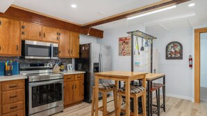 Une cuisine dotée de meubles en bois, d’appareils électroménagers en acier inoxydable et d’une table en bois avec des tabourets de bar.
