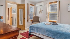 Une chambre à coucher avec un lit, une chaise, une commode en bois et un tapis rouge.