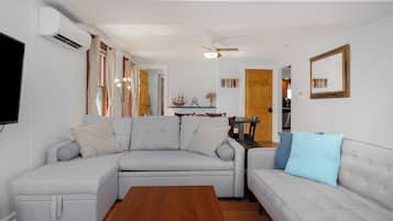 A living room with a grey sectional sofa, a wooden coffee table, and a ceiling fan.