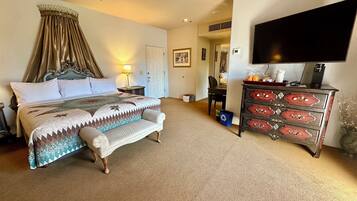 A hotel room with a large bed, a desk, a dresser, and a TV.