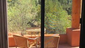 Un balcón con mobiliario de mimbre y vistas a un paisaje montañoso.