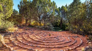 Un laberinto espiral de piedra en un área boscosa.