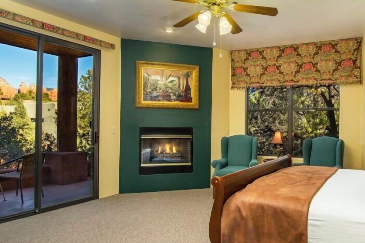 Un dormitorio con chimenea, ventilador de techo y un ventanal con vistas al exterior.