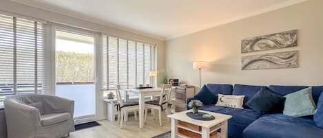 A living room with a sofa, a chair, a dining table, and a lamp.