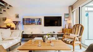 A modern living room with a sofa, armchairs, a coffee table, and a TV mounted on the wall. - Les Jardins du Val by Interhome (Dinard)