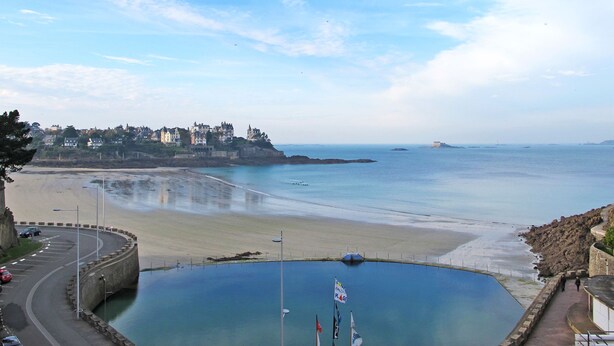 A coastal view with a beach, a roundabout, and a building complex on a cliff. - Les Jardins du Val by Interhome (Dinard)