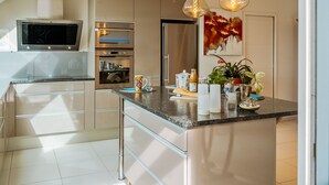 A modern kitchen with stainless steel appliances, a marble countertop, and pendant lighting. - Les Jardins du Val by Interhome (Dinard)