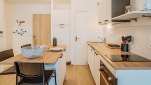 Una cocina moderna con encimera de madera, horno integrado y fregadero. Hay una zona de comedor con una mesa y sillas.