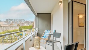Un balcón con mesa, sillas, un taburete pequeño y una lámpara decorativa.
