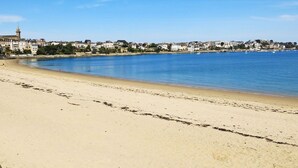 Una spiaggia con cielo azzurro, spiaggia sabbiosa e edifici sullo sfondo.