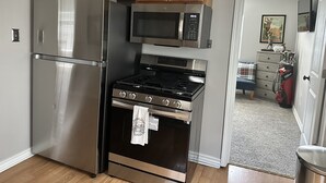 A kitchen with stainless steel appliances, wooden cabinets, and a microwave.