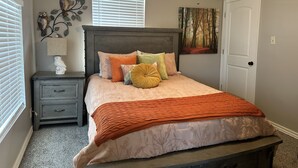 A bedroom with a bed, nightstand, dresser, and a ceiling fan.