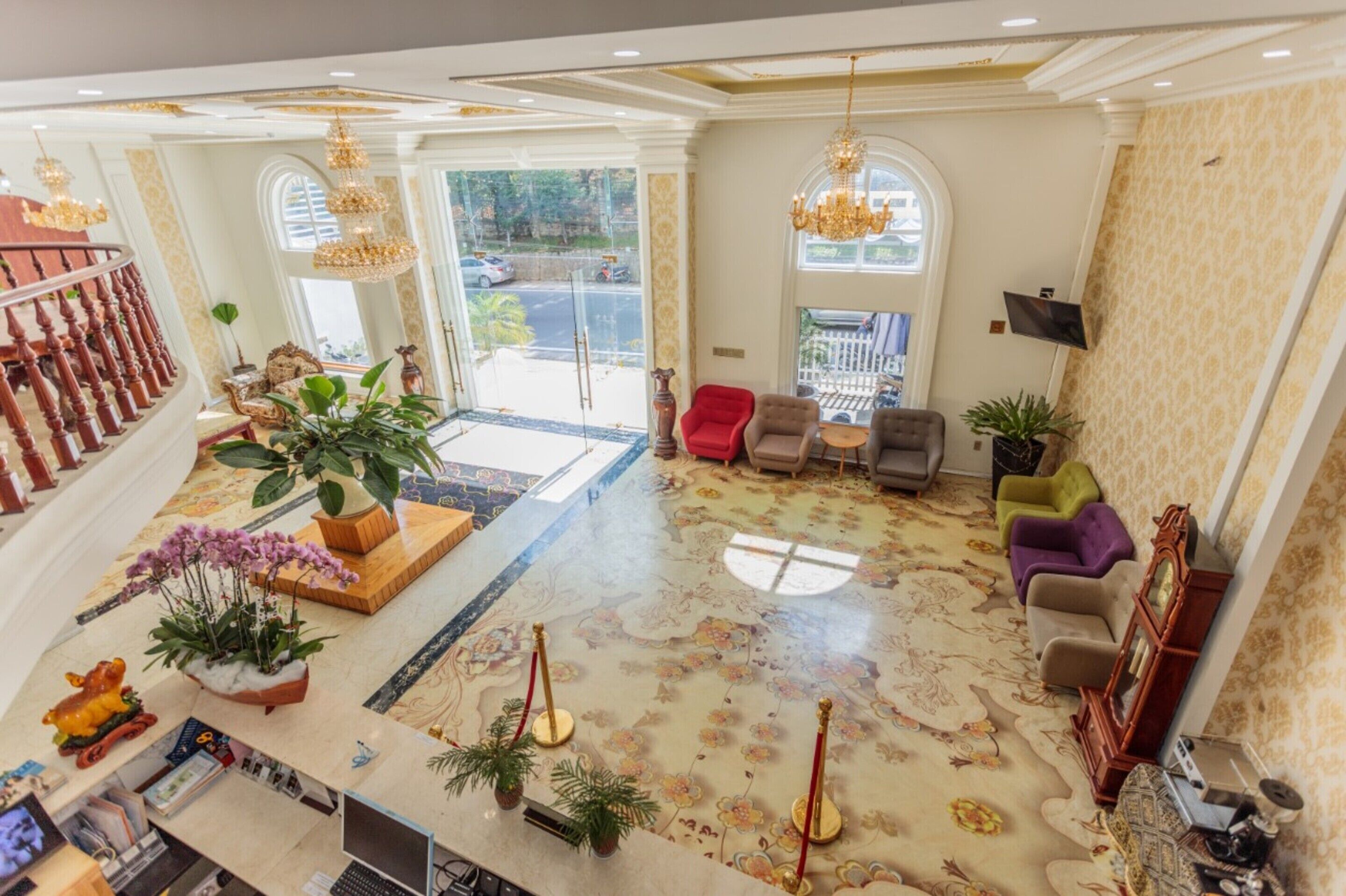 A spacious lobby with a grand staircase, a reception desk, and a seating area with multiple chairs.