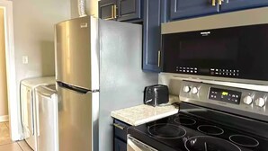 Cozinha equipada com geladeira de aço inoxidável, micro-ondas, torradeira e fogão.