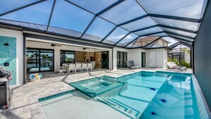 Ein moderner Poolbereich im Freien mit einer verglasten Terrasse, einer Sitzecke und Blick auf die umliegende Landschaft.