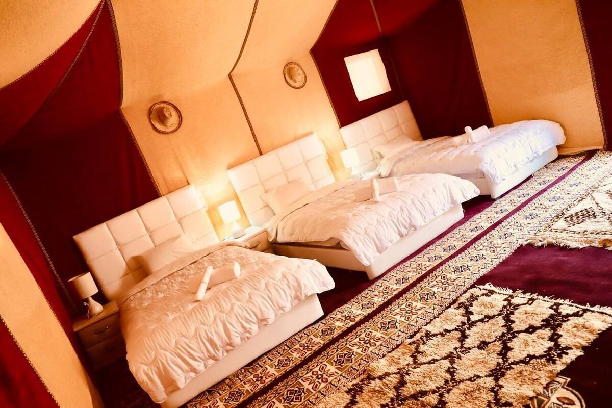 A hotel room with a large bed, two bedside tables, and a patterned rug.