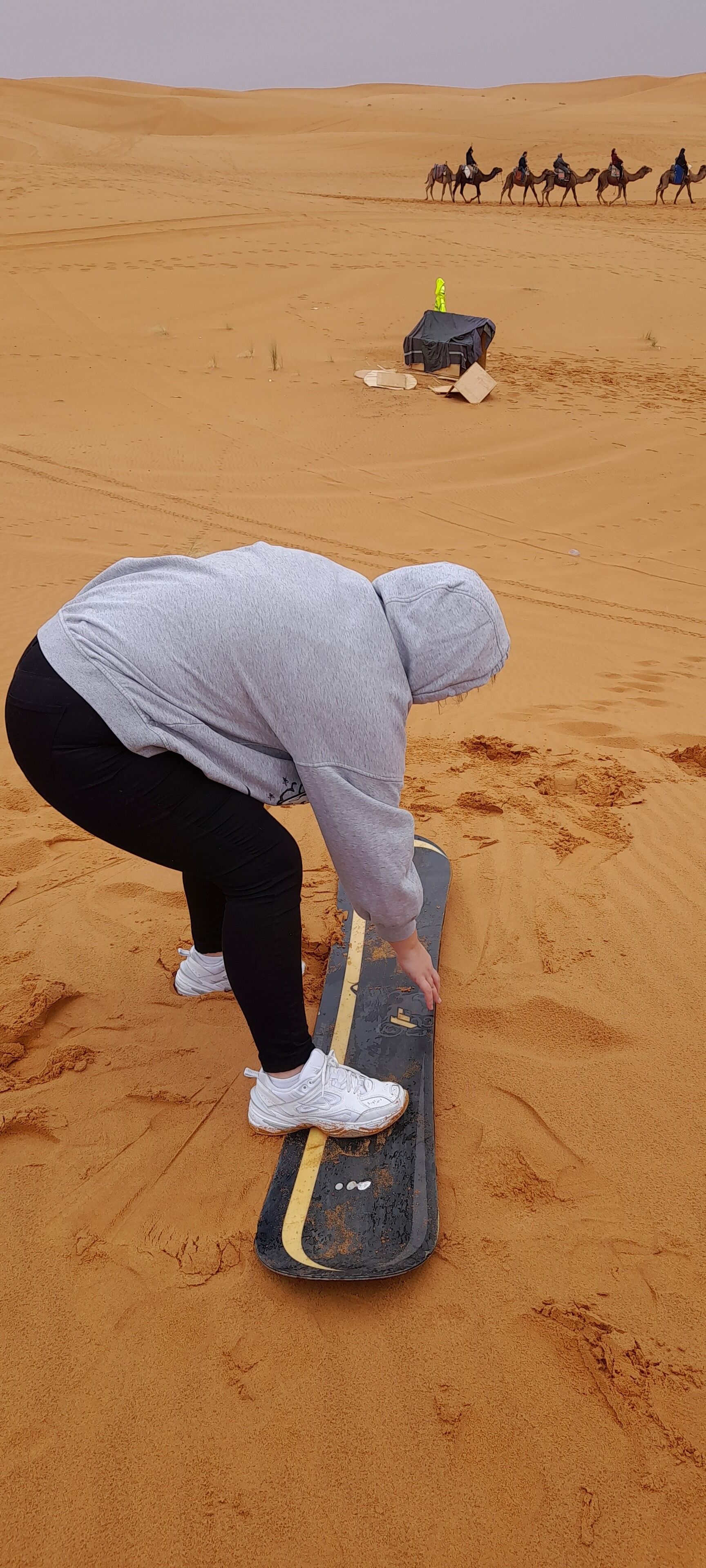 A person riding a skateboard on sand.