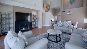A spacious living room with a fireplace, a ceiling fan, and a staircase leading to an upper level. - Rare 3 FULL bathroom home in golf community W/ private pool. Experienced Host. (Mesa)