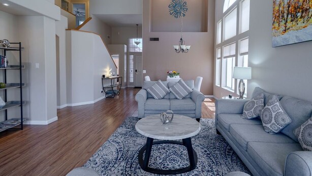 A spacious living room with a grey sofa, a round coffee table, and a patterned rug. - Rare 3 FULL bathroom home in golf community W/ private pool. Experienced Host. (Mesa)