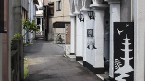 Een smalle steeg met een hotelingang, een fiets en een zwart-wit bord met Japanse tekens.