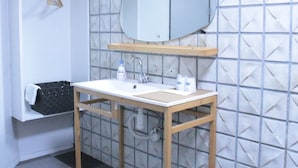 Een badkamer met een wit wastafelmeubel, een spiegel en een handdoekhouder.