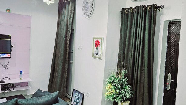 A modern living room with a sofa, a round table, a potted plant, and a wall-mounted air conditioner. - Motalvin Court  (Lagos)