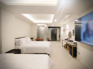 A hotel room with two beds, a desk with a chair, a TV, and a sliding door leading to a bathroom. - Bluebird Hotel (Incheon)