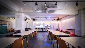A conference room with tables and chairs, a projector screen, and a wall with a light display.