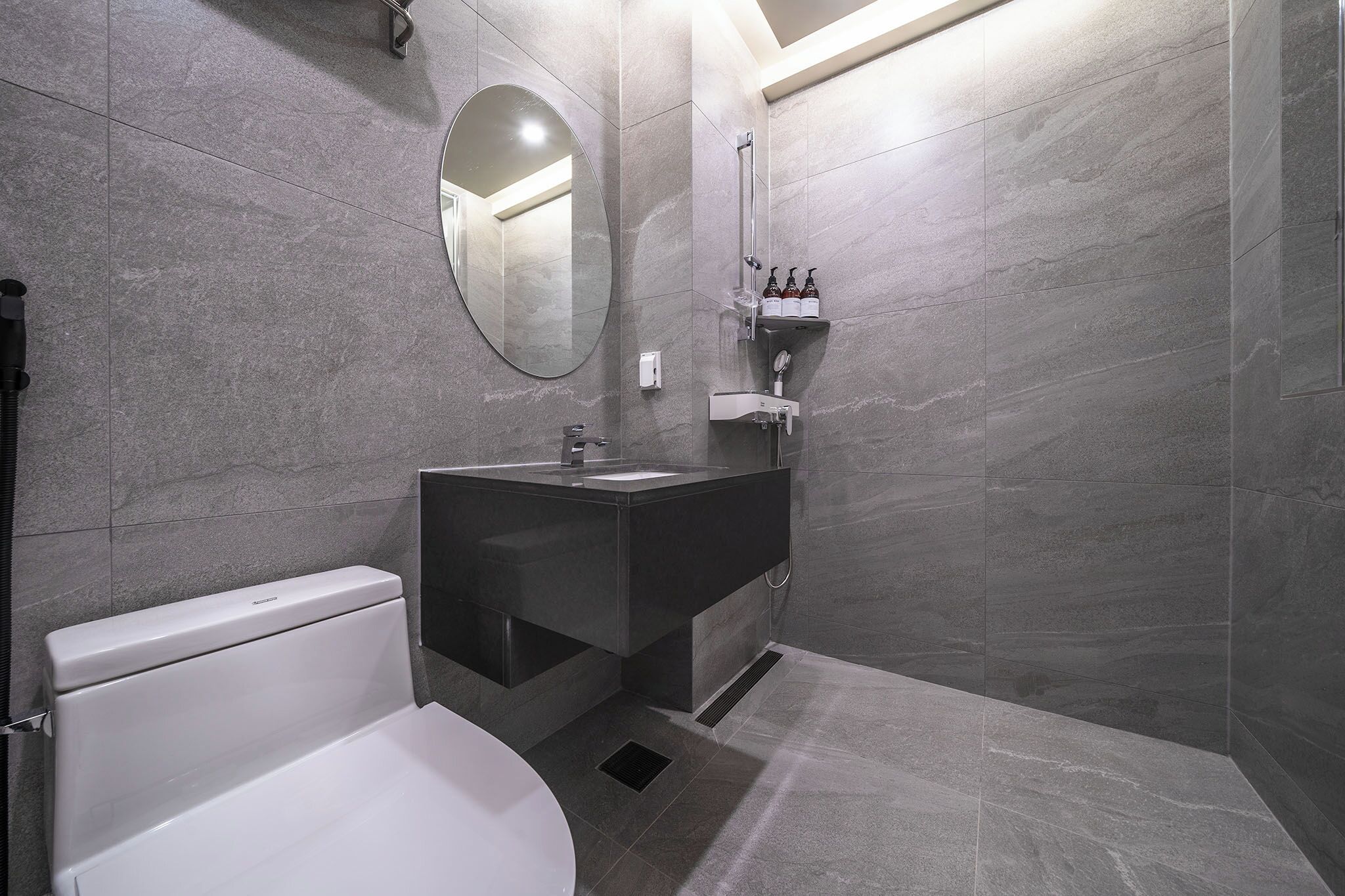 A modern bathroom with a toilet, sink, and mirror.