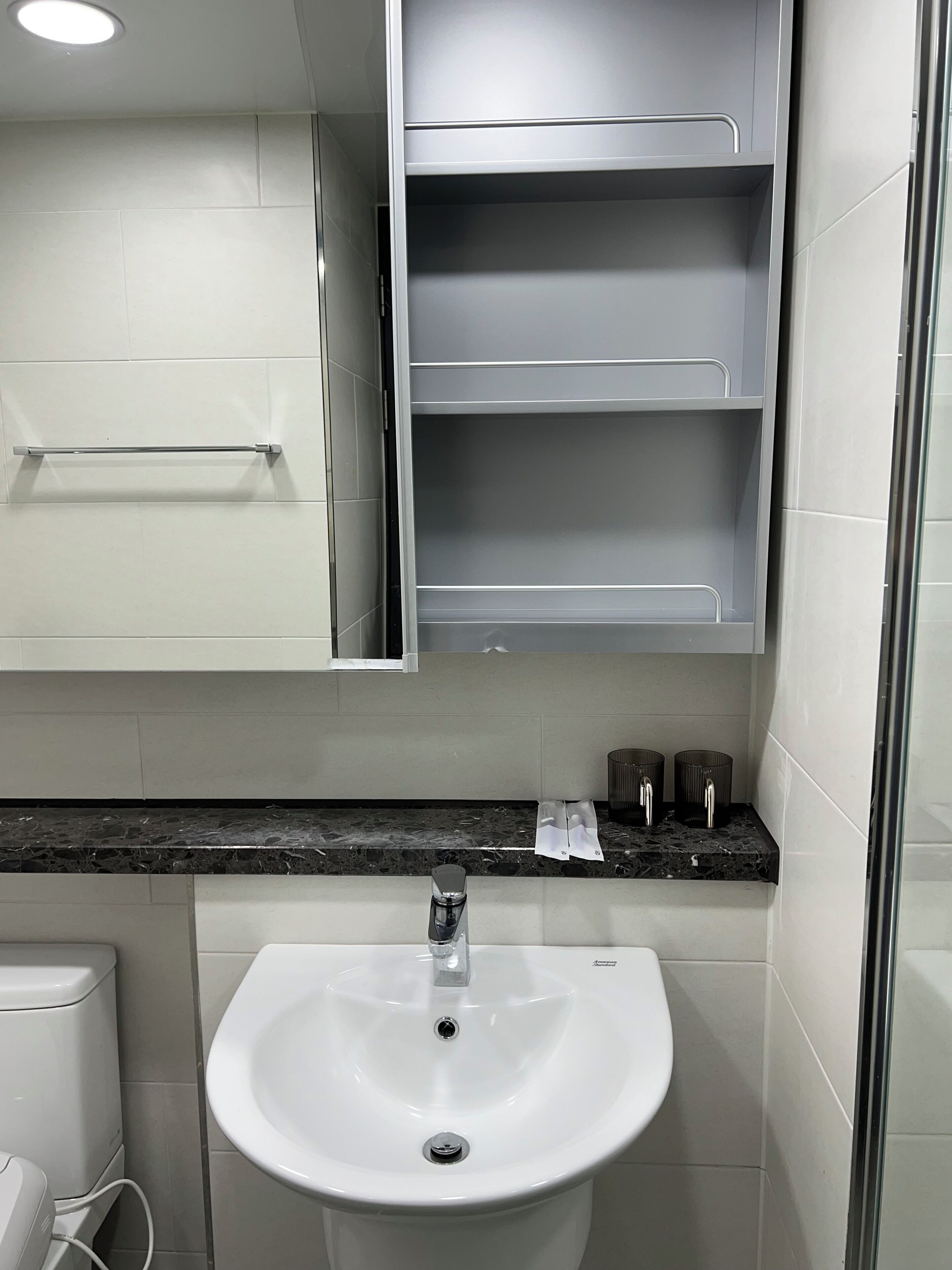 A bathroom with a white sink, a mirror, and a black countertop.