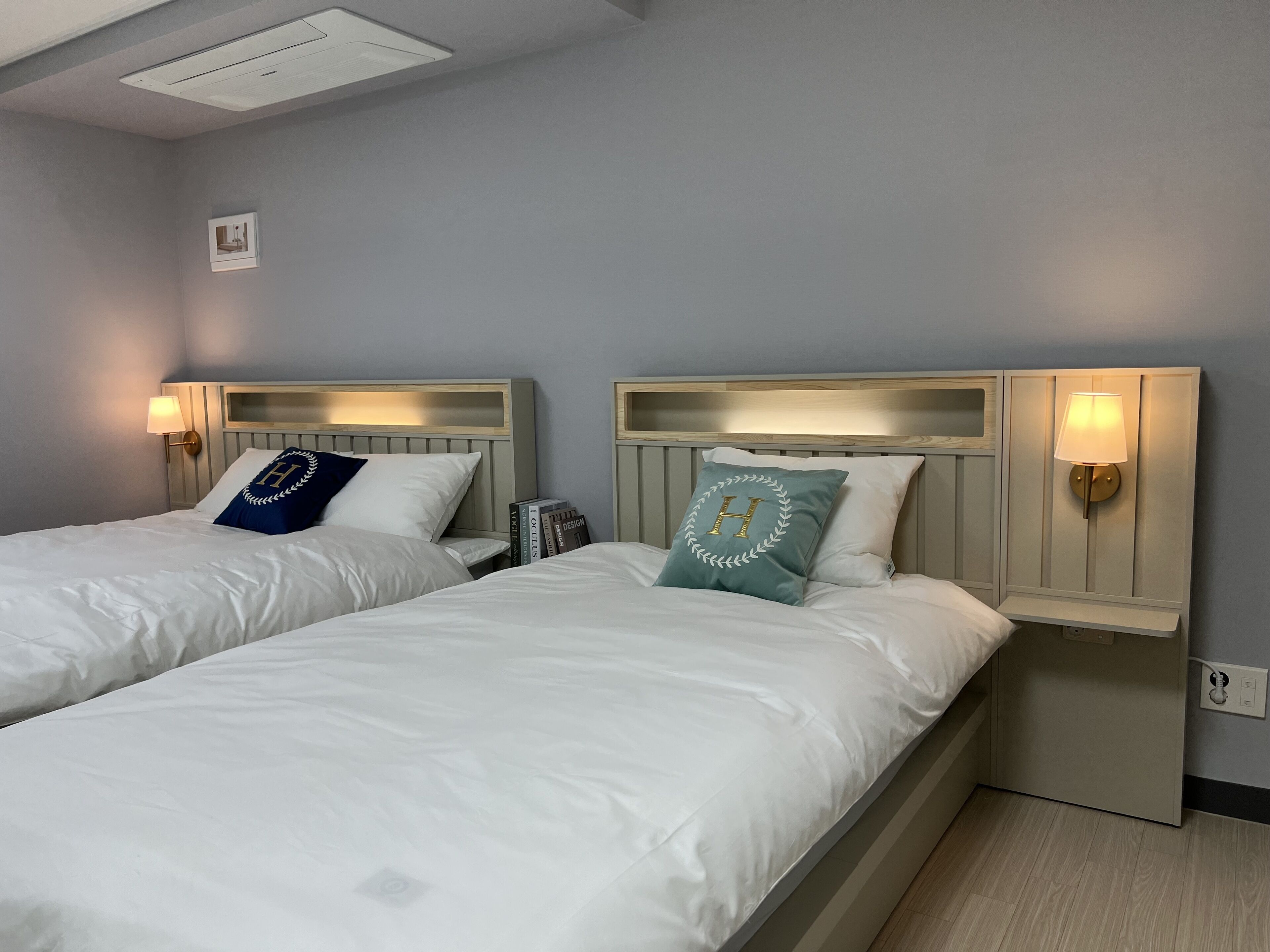 Two single beds with headboards, bedside lamps, and a small table with books.
