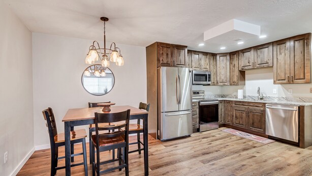 Una cocina moderna con armarios de madera, electrodomésticos de acero inoxidable y un comedor con mesa y sillas de madera.