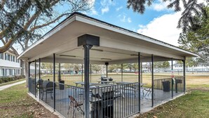 Un patio techado al aire libre con una parrilla, asientos y un área cercada.