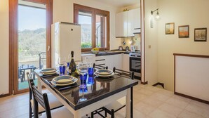 A modern kitchen with a dining area, featuring a refrigerator, stove, and large windows. - Villaggio 5 Terre by Interhome (Pignone)