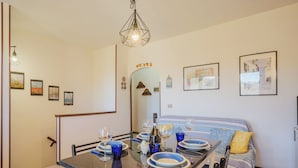 A dining area with a table set for four, a sofa, and a mirror. - Villaggio 5 Terre by Interhome (Pignone)