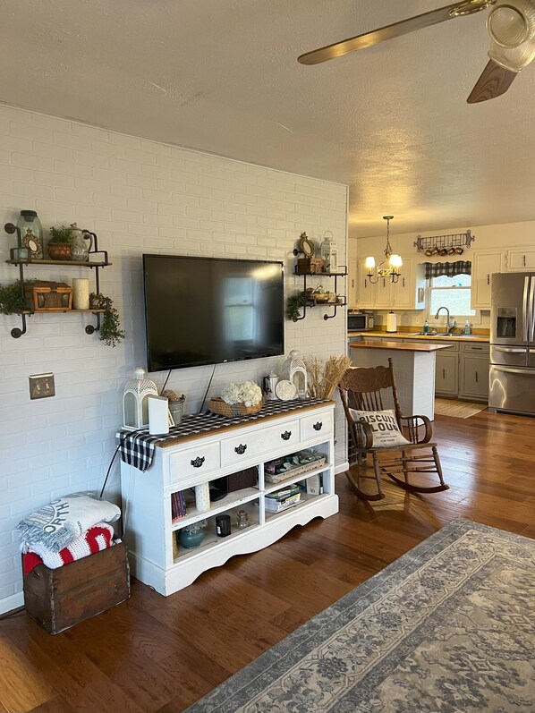 A modern living room with a flat-screen TV, wooden entertainment unit, and a cozy seating area with a rocking chair. - Mountain House near the Appalachian Trail, Watauga Lake, Bristol, & Johnson City (Hampton)