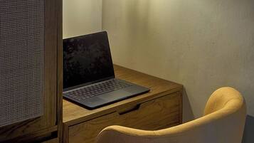 Escritorio de madera con una laptop, una lámpara y una silla en una habitación con pared texturizada.