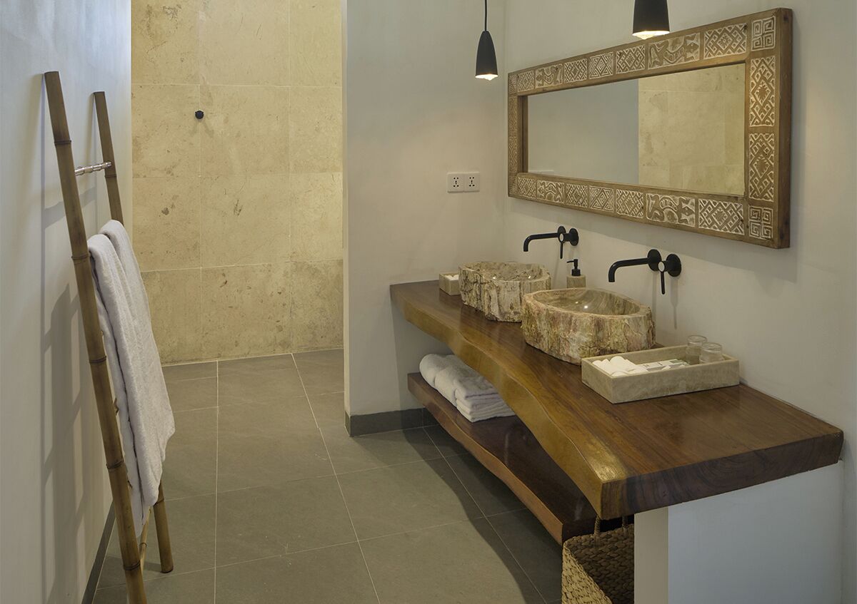 Un baño con tocador de madera, dos lavamanos, un espejo grande y una zona de ducha.