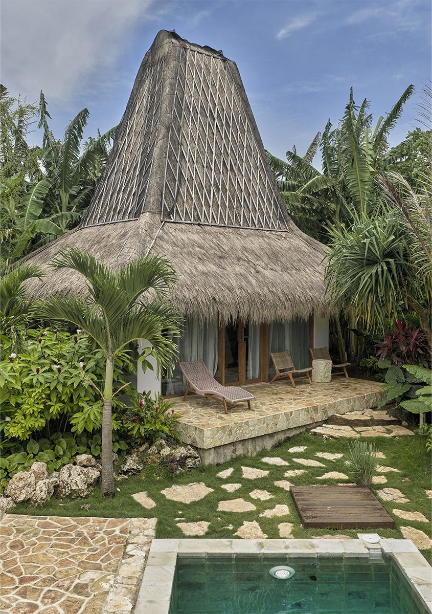 A thatched-roof bungalow with a pool, surrounded by tropical vegetation.