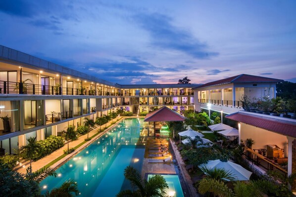 A hotel with a swimming pool, outdoor seating, and a covered area. - Elysium Suite (Siem Reap)