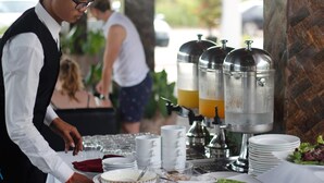 A buffet setup with multiple drink dispensers, plates, and bowls. - Elysium Suite (Siem Reap)