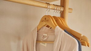 A wooden hanger with a tag labeled "SUM ARIKO". - Sun Aeriko (Tinos)