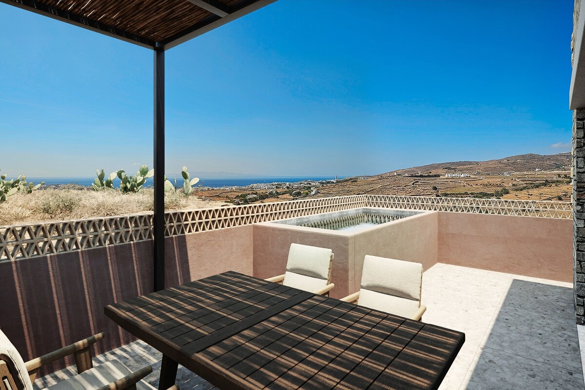 A terrace with a table and chairs, a pool, and a view of the countryside.
