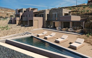 Una casa moderna con piscina, zona de estar exterior y fachada de piedra.