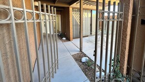 Zona exterior coberta amb una reixa de metall, un camí de formigó i un petit jardí amb roques i plantes.
