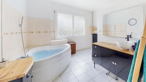 A modern bathroom with a freestanding bathtub, a large mirror, and a wooden vanity. - 3 bedroom stunning home in Lanvaudan (Lanvaudan)